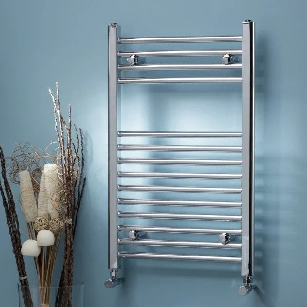 Chrome towel radiator mounted on a blue wall with decorative elements.