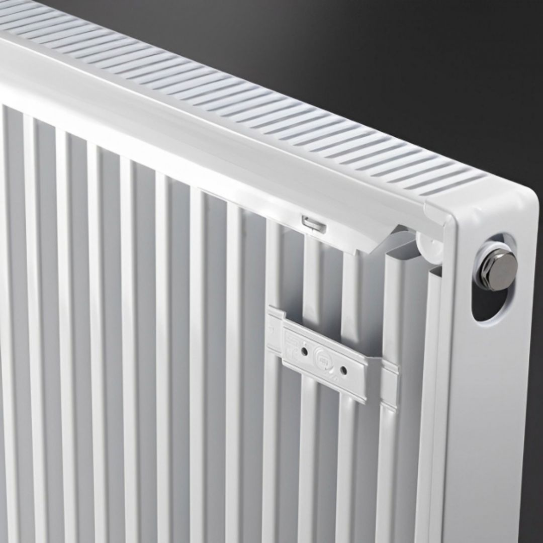 Close-up of a white metal radiator with vertical fins, a top cooling grille, and a silver adjustment knob against a dark background.