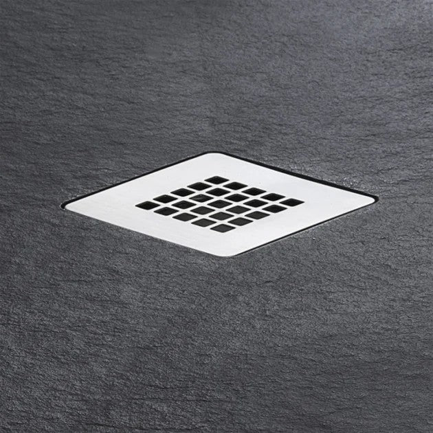 A square metal shower drain with a grid pattern, set into a dark gray slate-textured surface.