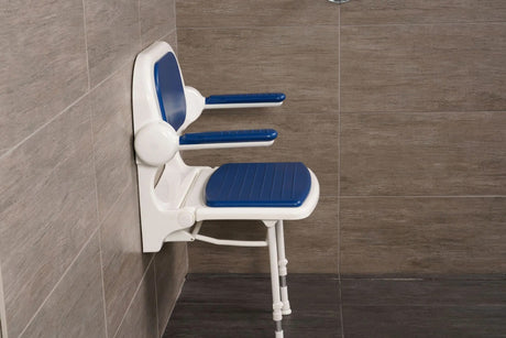 Wall-mounted shower seat with blue cushions in a tiled bathroom.