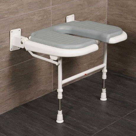 A wall-mounted bathroom safety seat with a gray molded seat cushion and white frame, shown attached to a tiled wall in a bathroom setting.