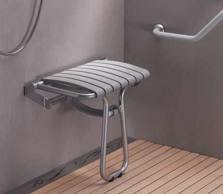 Foldable shower seat mounted on a wall in a bathroom with wooden floor.
