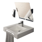 a titled bathroom mirror above a sink against a white background
