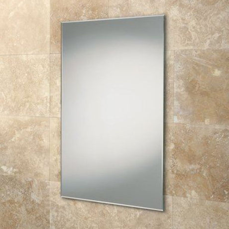 A rectangular wall-mounted mirror with a slim silver frame, shown against a beige stone tile wall.