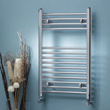Chrome towel radiator mounted on a blue wall with decorative elements.