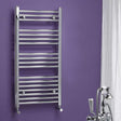 Chrome towel radiator against a purple wall with bathroom fixtures.