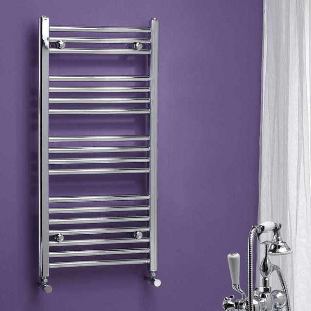 Chrome towel radiator against a purple wall with bathroom fixtures.