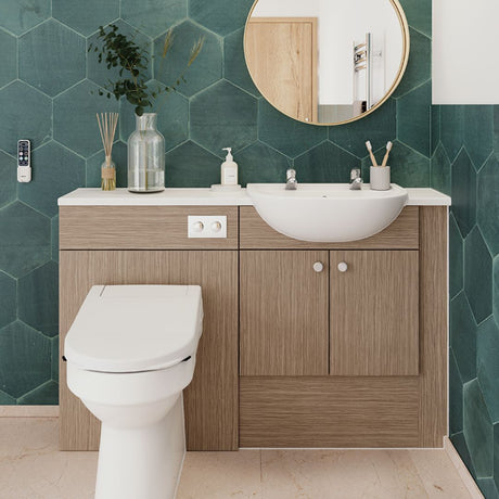 A modern bathroom vanity setup with a white ceramic sink and toilet, set against a dark green hexagonal tiled wall. The vanity features light oak wood grain cabinets and drawers with silver knobs.
