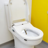 A white modern bidet toilet with the lid open, showing a clean seat and clean water in the bowl, set against a white wall and a bright yellow door.