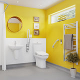 Bright modern bathroom with bright yellow walls, white sink and toilet, gray floor, wall-mounted towel rail, round mirror, small framed wall art, and a potted plant.