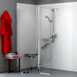 A modern corner shower enclosure with a clear glass door and chrome shower system, shown installed in a bathroom with gray walls, a red robe, a small table, and a bench.