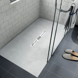 Modern bathroom shower tray with a shower area featuring a drain and tiled walls.