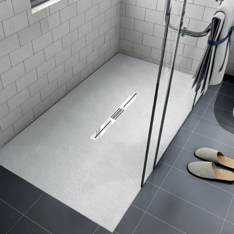 Modern bathroom shower tray with a shower area featuring a drain and tiled walls.