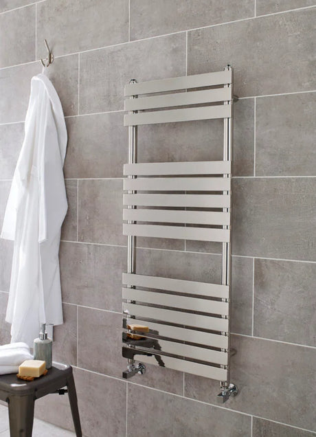 Metal towel radiator mounted on a tiled bathroom wall with a white bathrobe and stool.