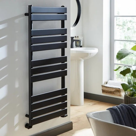 Black towel radiator in a bathroom setting with a window and plant.