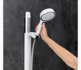 Hand holding a white handheld shower head against a dark gray wall.