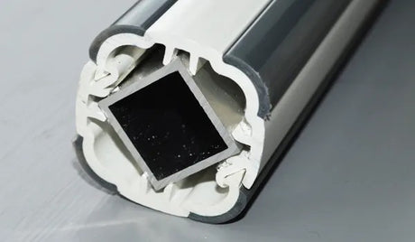 Close-up of a metallic profile with a black square insert on a gray background