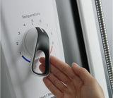 Hand adjusting a temperature dial on a machine with a blurred background