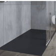 Black shower tray in a shower enclosure with gray walls.