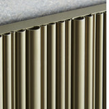 Close-up of a ribbed metallic panel in a warm bronze tone, with vertical channels and a textured gray surface at the top.