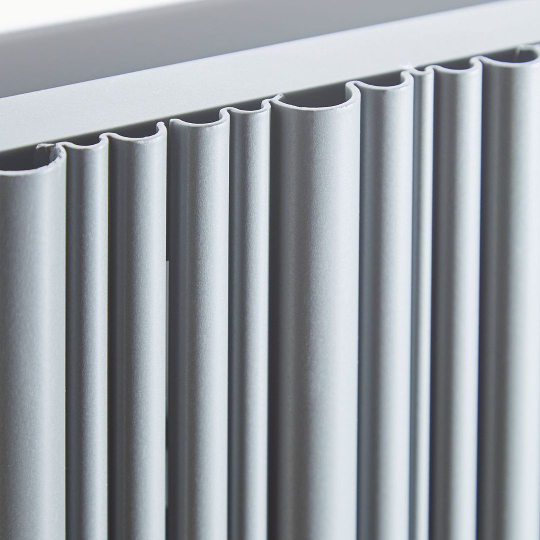 Close-up of a modern radiator with matte white-finished fins and a matching top frame.