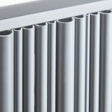 Close-up of a modern radiator with matte white-finished fins and a matching top frame.