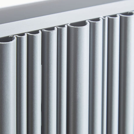 Close-up of a modern radiator with matte white-finished fins and a matching top frame.