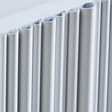 Close-up of a modern white pleated radiator panel hanging against a white wall.