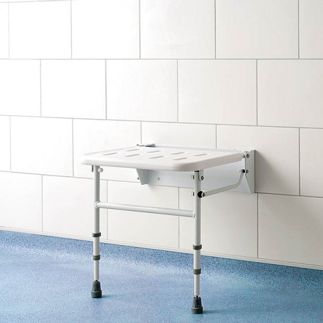 Foldable shower seat against a white tiled wall with a blue floor.