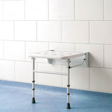 Foldable shower seat against a white tiled wall with a blue floor.