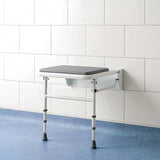Wall-mounted adjustable shower seat against a white tiled wall.