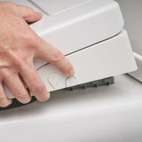 A close-up of a person's hand pressing a small button on a white bidet toilet seat to remove