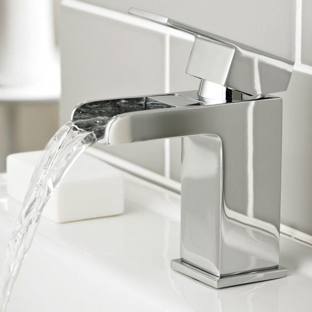 Chrome bathroom faucet with water flowing in a bathroom setting