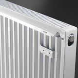 Close-up of a white metal radiator with vertical fins, a top cooling grille, and a silver adjustment knob against a dark background.