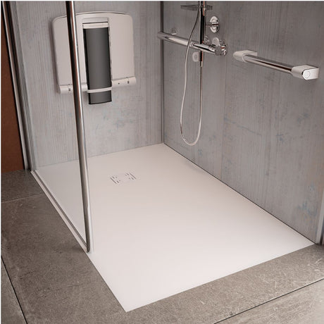 An accessible shower stall with a white low-profile shower base, chrome grab bars, a handheld shower head, and a wall-mounted seat, shown in a modern bathroom setting.