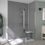 A modern walk-in shower enclosure with a clear glass door and frame, chrome shower hardware, a white bench seat, and gray textured walls in a bathroom setting.