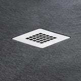A square metal shower drain with a grid pattern, set into a dark gray slate-textured surface.