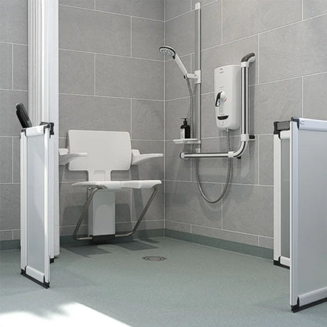A modern wetroom shower setup with a white fold-down shower chair, wall-mounted shower system, gray tiled walls, vinyl floor and white-framed glass shower doors on both sides.